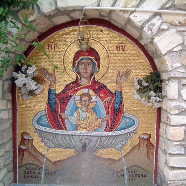 Mosaic of Virgin Mary and baby Jesus surrounded by flowers and stone arch.