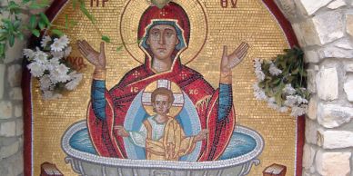 Mosaic of Virgin Mary and Child Jesus in a religious setting with flowers.
