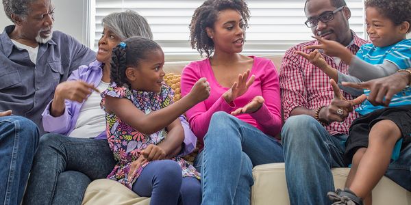Family playing rock paper scissors on the couch.