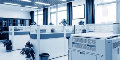 Modern office cubicles with large windows and a printer.