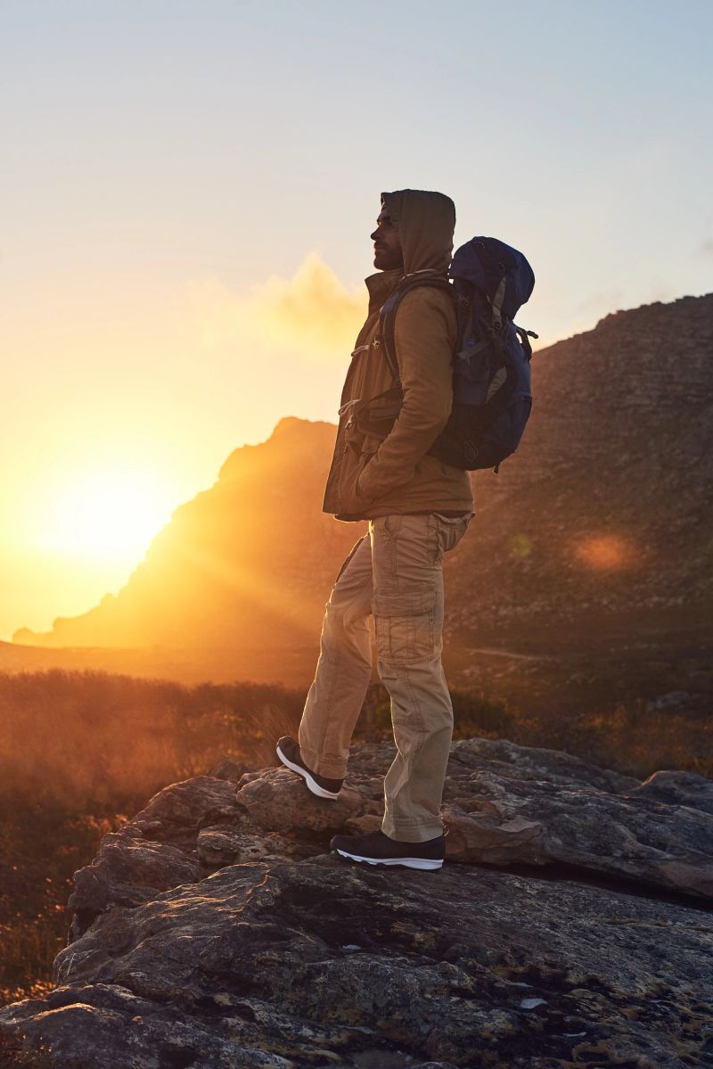 Shot of a hiker on top of a mountain taking in the views of the morning sun