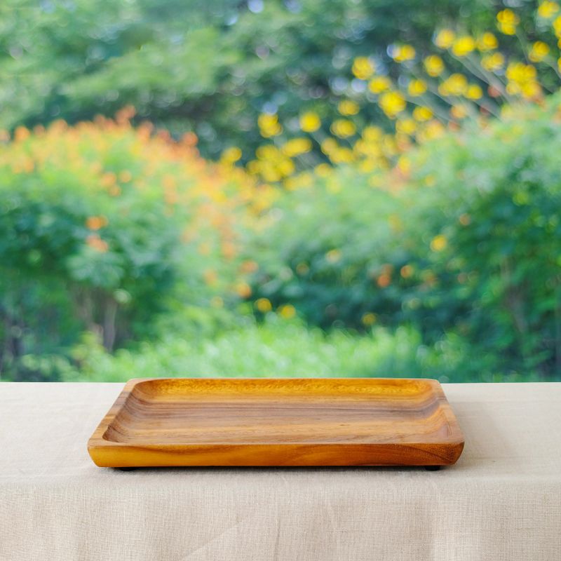 Empty wooden tray on table with linen tablecloth over blur tree background, for food and product display montage, template
