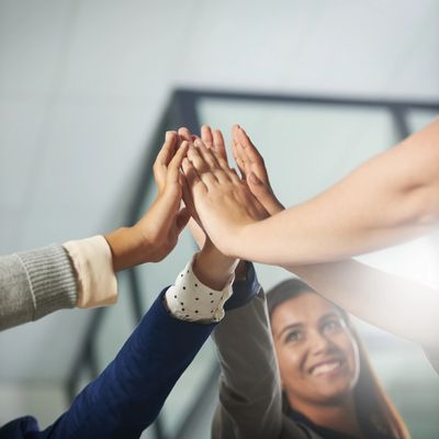 Group of people joining hands in a high-five gesture symbolizing teamwork.