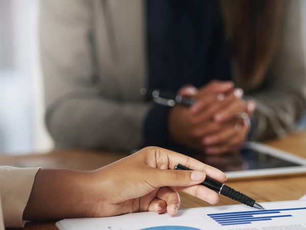 Person pointing at a bar chart on a report during a meeting.
