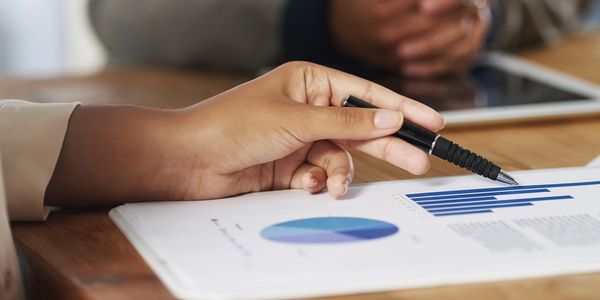 Hand pointing at a bar chart on a document during a meeting.