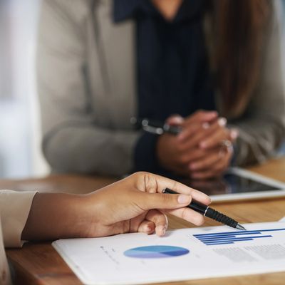 Person pointing at a bar chart on a report during a meeting.