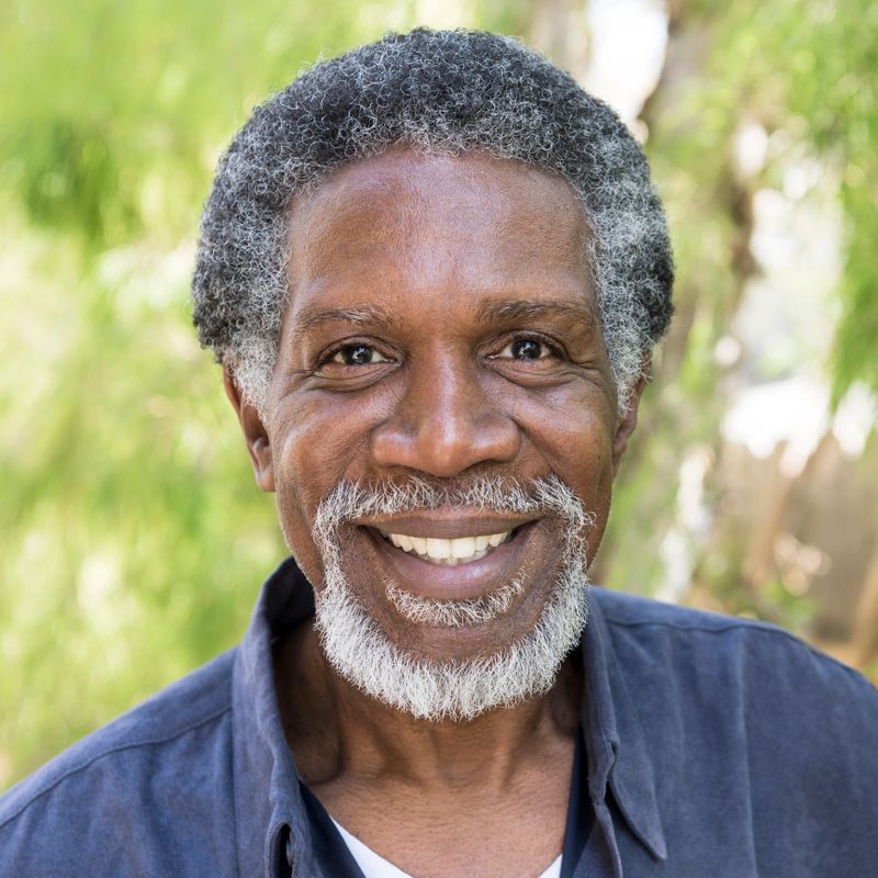 The man is smiling towards the camera with a cheerful expression