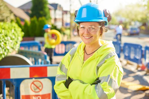 Smiling female construction worker wearing safety gear at a work site.