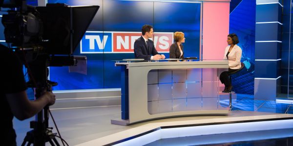 Interview sur le plateau TV News avec trois personnes.