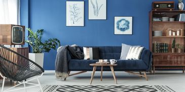 BLUE WALLS WITH BLUE COUCH AND FURNITURE AND WHITE CARPET