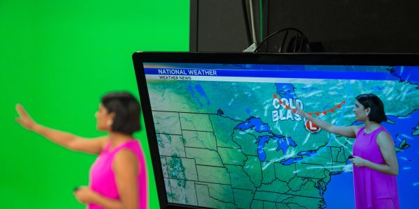 Weather reporter presenting the forecast in front of a green screen.