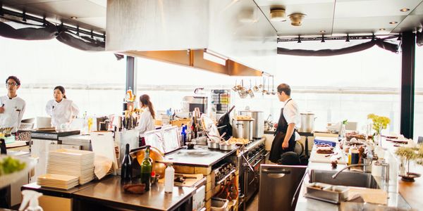 Busy modern kitchen with chefs preparing meals and organized cooking stations.