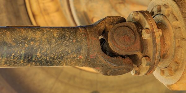 Close-up of a rusty universal joint on a vehicle's drive shaft.