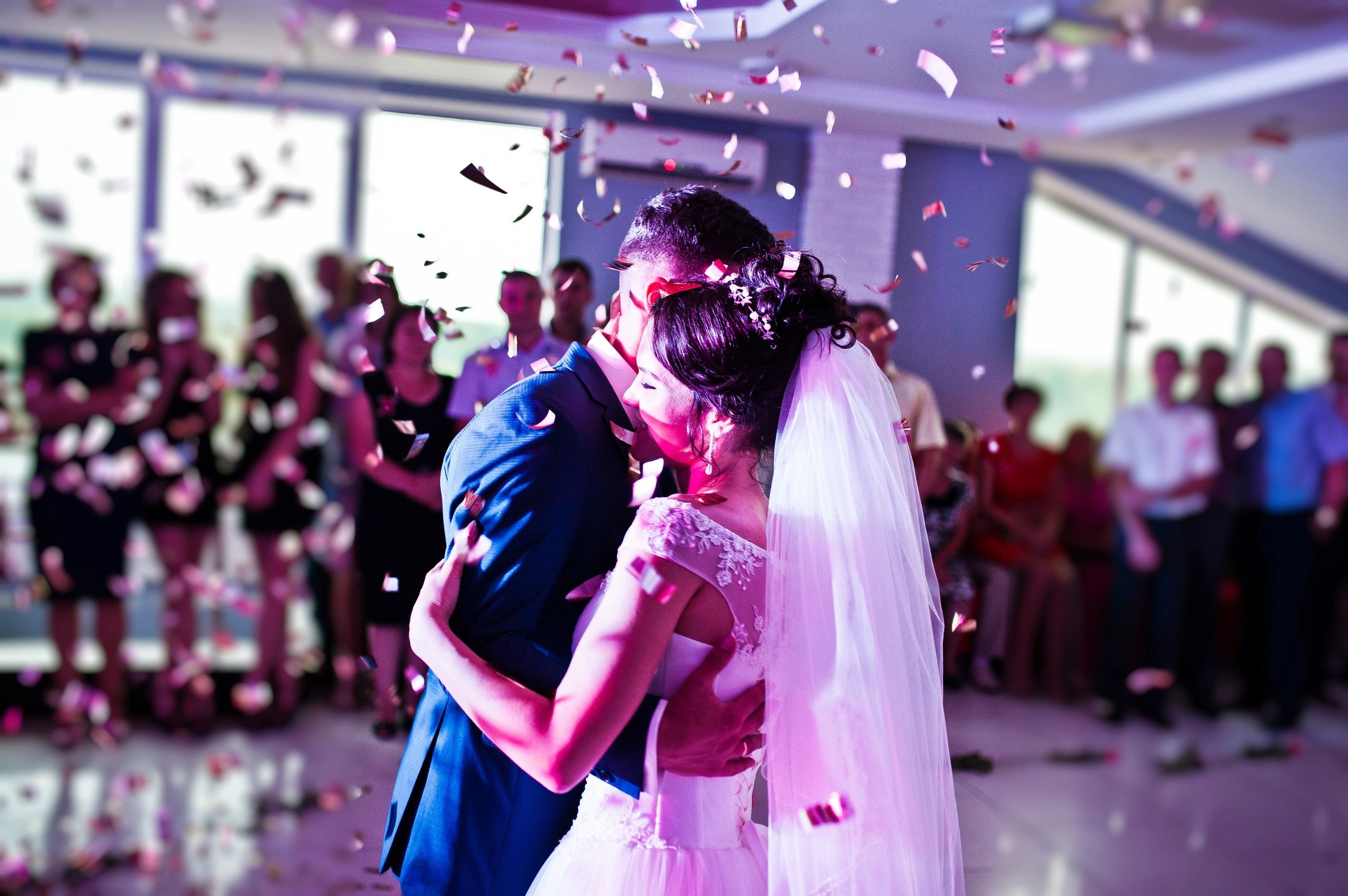 Bride and groom share a tender dance surrounded by falling confetti and guests.