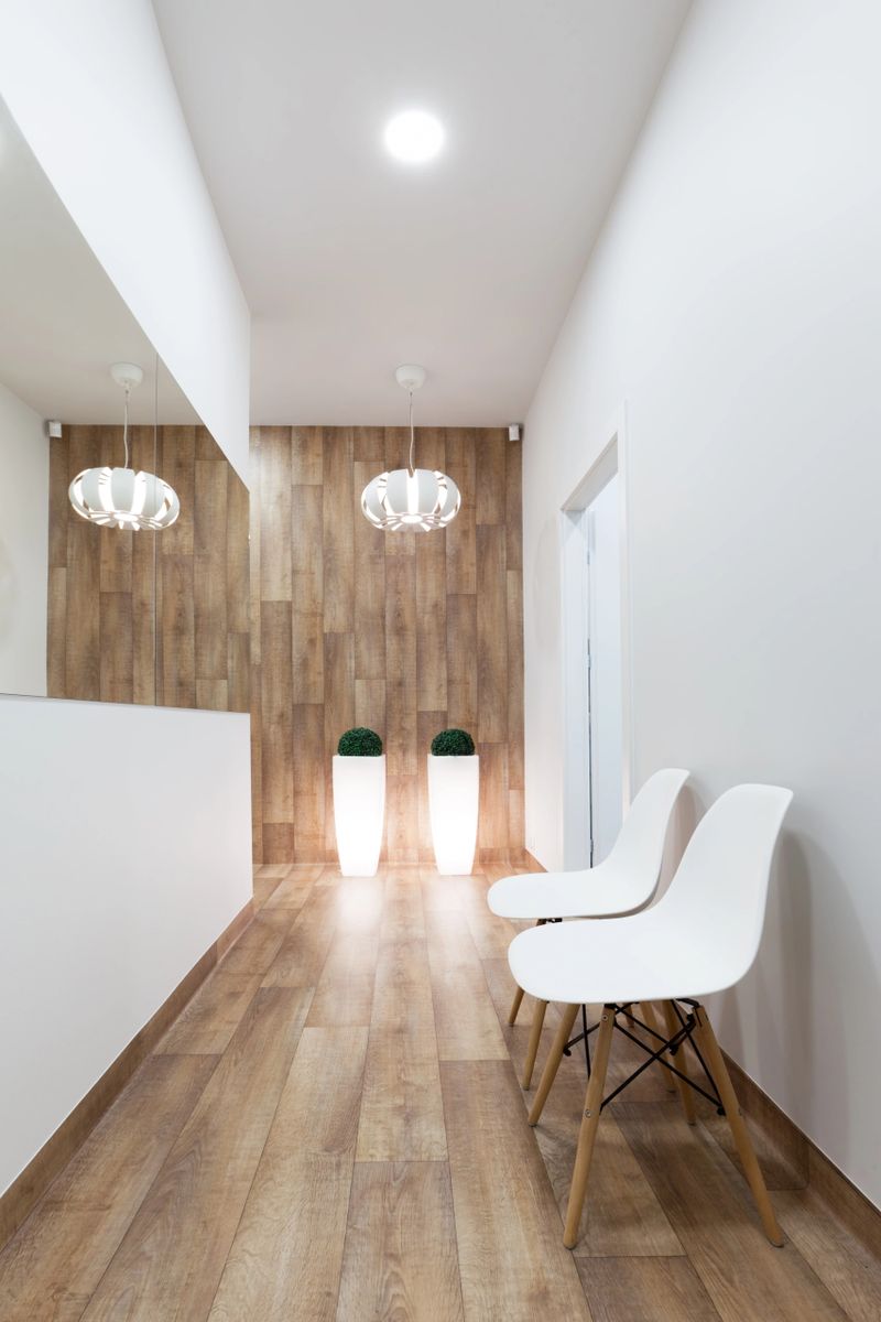 Modern waiting room, reception. Cozy minimalistic interior with seats, lights, mirror and parquet floor.