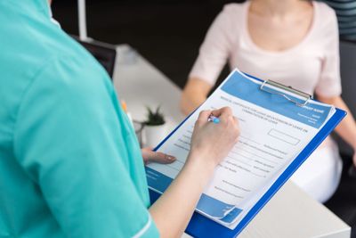 Medical professional fills out a leave certificate for a patient sitting across.