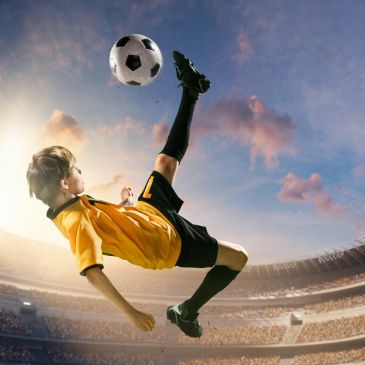 Young soccer player performing a bicycle kick in a stadium.