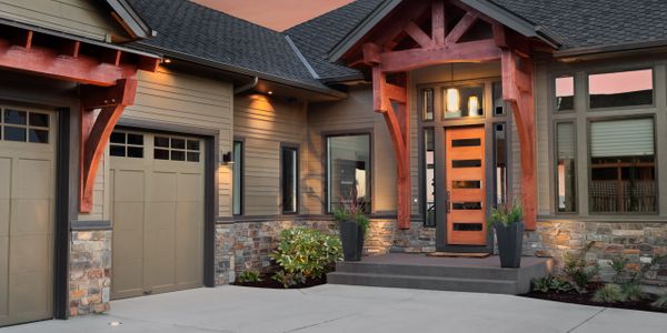 Modern house entrance with stone and wood accents at sunset.