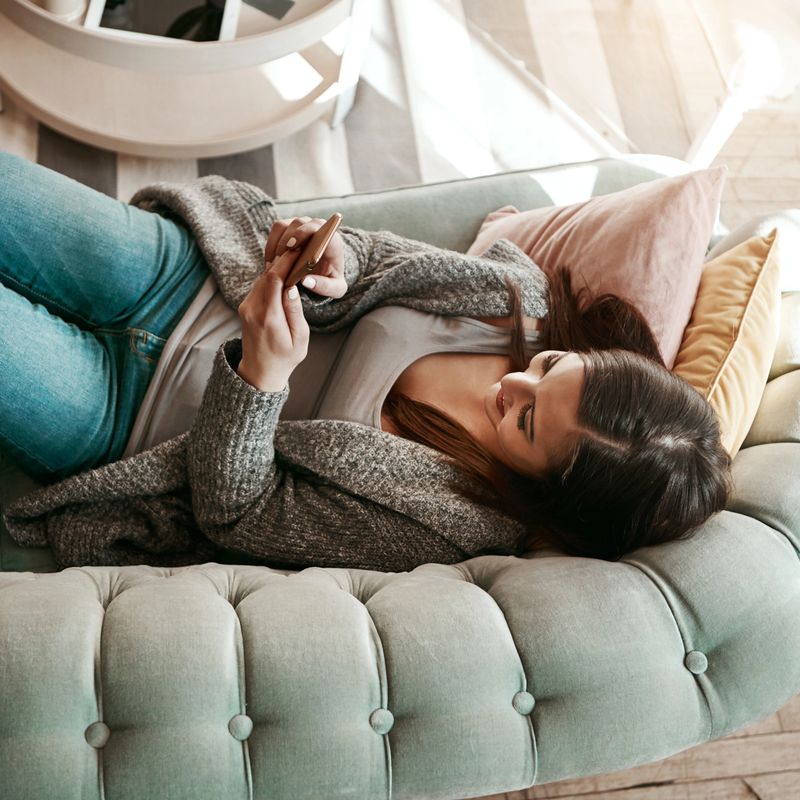 Shot of an attractive young woman using her cellphone while relaxing at home