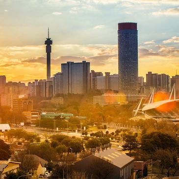 City skyline at sunset with tall buildings and a tower.