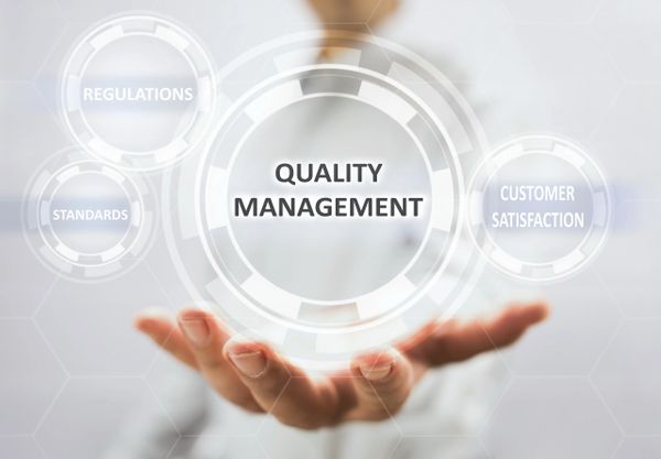 Hand presenting digital icons of quality management concepts.