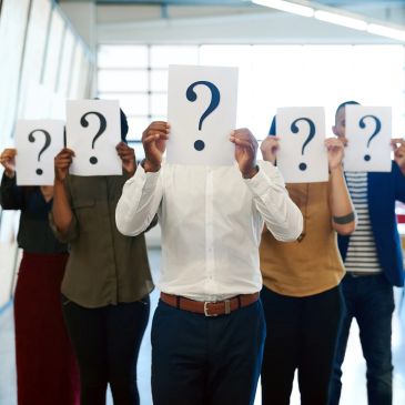 People holding question mark signs in front of their faces.
