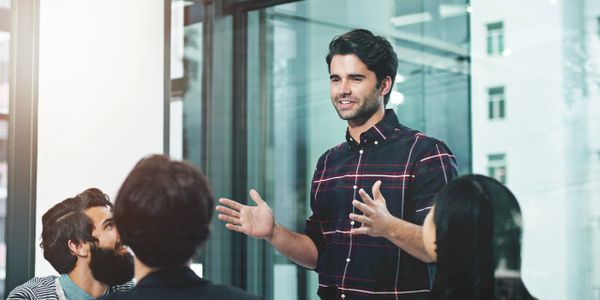 Man presenting to a group in a modern office meeting room.