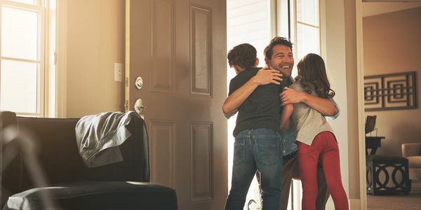 Father hugging his kids happily at home.