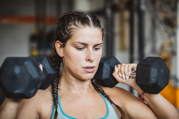 Woman lifting dumbbells at the gym with focused expression.