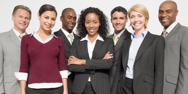 A diverse group of six professionals smiling and standing confidently together.