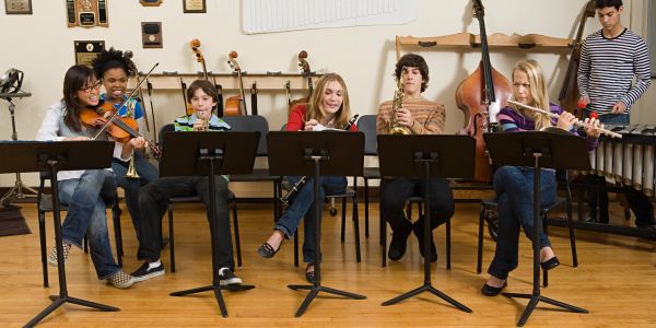 A group of young students playing various musical instruments in a band rehearsal.