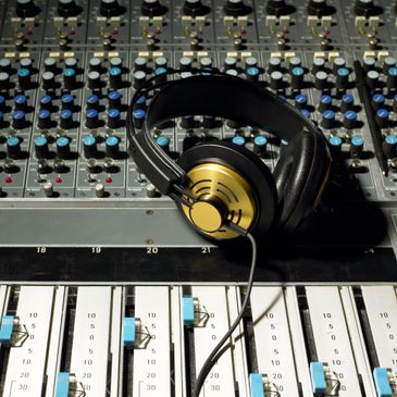 Black and gold headphones resting on a music mixing console.
