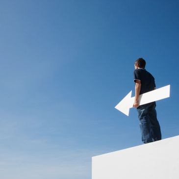 Hombre sosteniendo una flecha blanca mirando hacia el cielo.