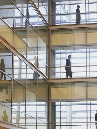 people walking in a glass walled office building