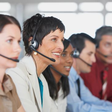 Call center representatives wearing headsets, engaged in customer service.