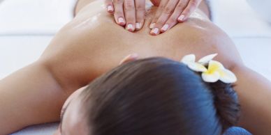 Person receiving a back massage with a flower in hair.
