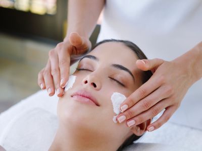 Woman enjoying a facial treatment with cream applied on her cheeks.