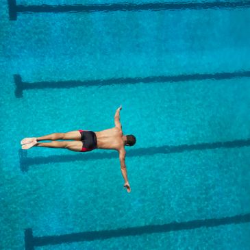 Man diving into a pool with arms outstretched.