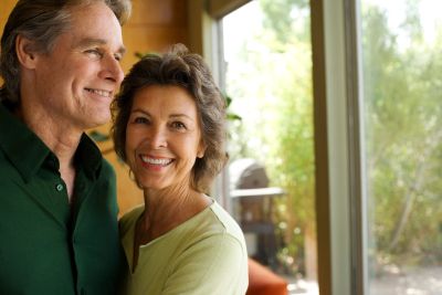Smiling middle-aged couple hugging indoors.