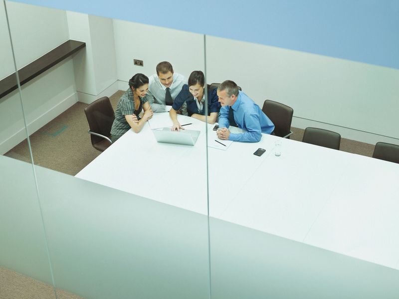 Four businesspeople at a table with documents and laptop