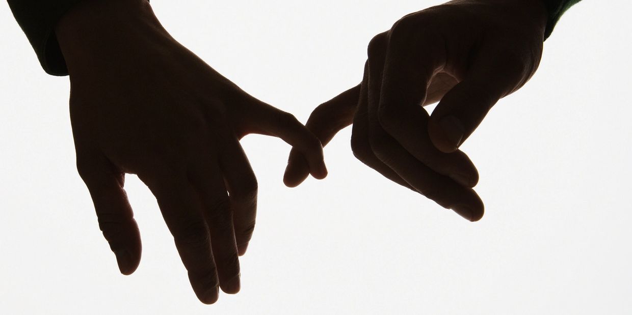 Two hands touching with fingers against a white background.