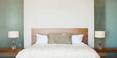 Minimalist bedroom with a wooden bed and matching lamps on floating nightstands.