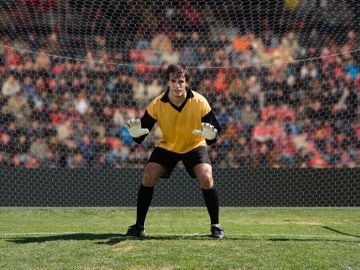 Goalkeeper ready in front of the goal net.