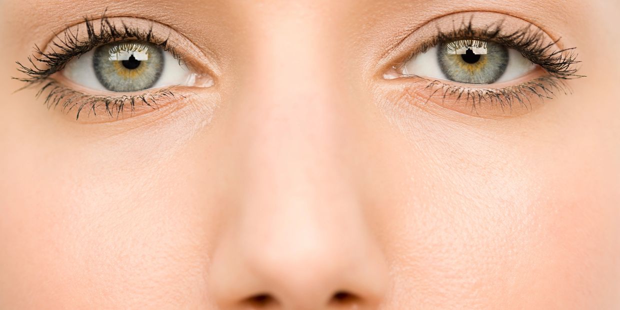 Close-up of expressive green eyes with detailed eyelashes and smooth skin.