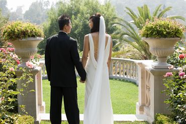 Bride and groom holding hands in a garden setting.