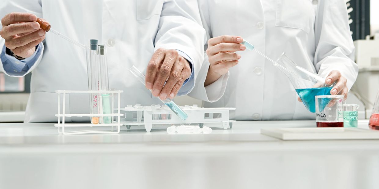 实验室中两位穿白大褂的科学家操作化学试剂。