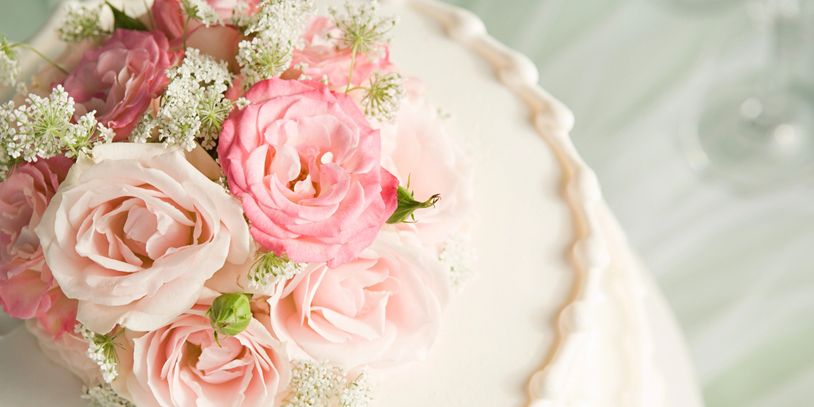 Elegant white cake adorned with pink roses and delicate white flowers.