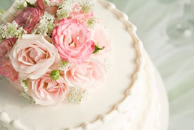 Elegant white cake adorned with pink roses and delicate white flowers.