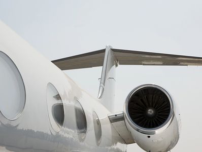 Close-up of a private jet's engine and windows under a clear sky. Private jet