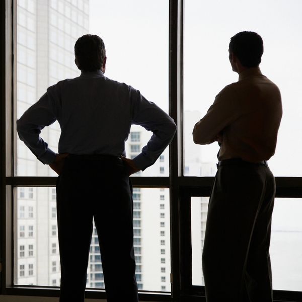 Dos hombres de espaldas mirando por una ventana grande.